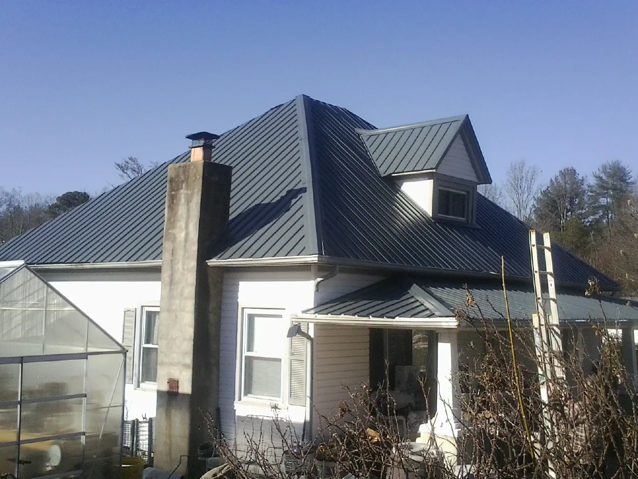 Dark blue standing seam metal roof on a white farmhouse with dormer — Slate & Tile Roof Repair by Roofing Brothers in Westminster