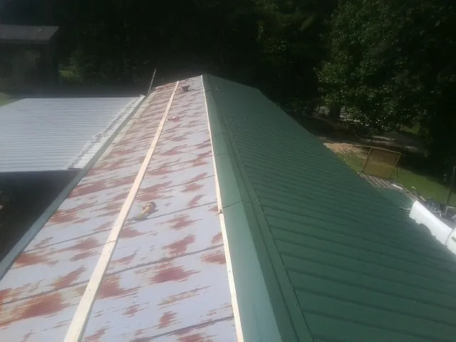 Old rusted panels beside newly installed green metal roofing — Wind Damage Roof Repair by Roofing Brothers in Westminster